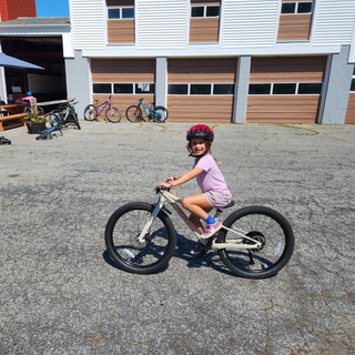 Child riding a bicycle in front of a building with bicycles parked outside